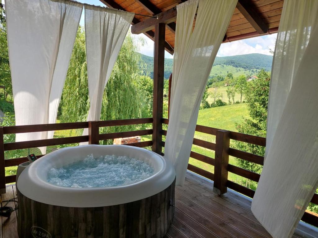 a large wooden tub on a deck with a fence at B&B Green Serenity Plitvice Lakes in Plitvička Jezera