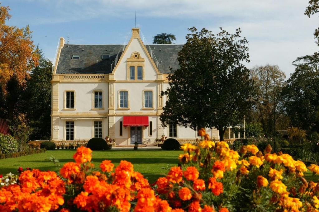 a large white house with flowers in the foreground at Le Manoir de Bellerive in Le Buisson de Cadouin