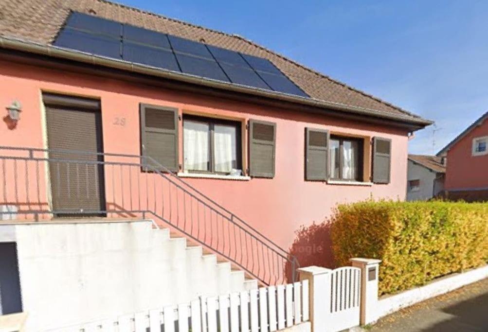 een roze huis met zonnepanelen op het dak bij Maison entre ville et montagne in Valdoie