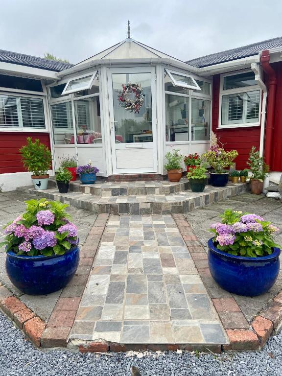 a house with pots of plants in front of it at Barrow Harbour studio apartment in Tralee