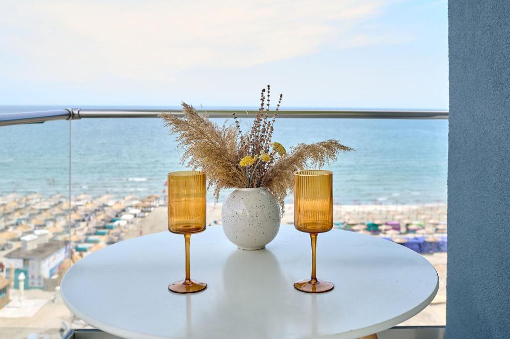 een tafel met twee kaarsen en een vaas erop bij Paradise Sea View 2BD apt Spa n Pools beach resort in Mamaia Nord – Năvodari