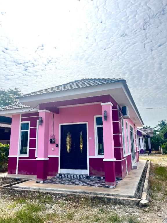 ein kleines rosa Haus mit einer schwarzen Tür in der Unterkunft Nazla Homestay Pendang 2 in Pendang