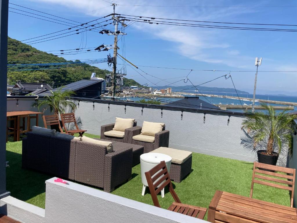d'une terrasse avec des chaises et des tables et une vue sur l'eau. dans l'établissement ロハスResort宮浦, à Fukuoka