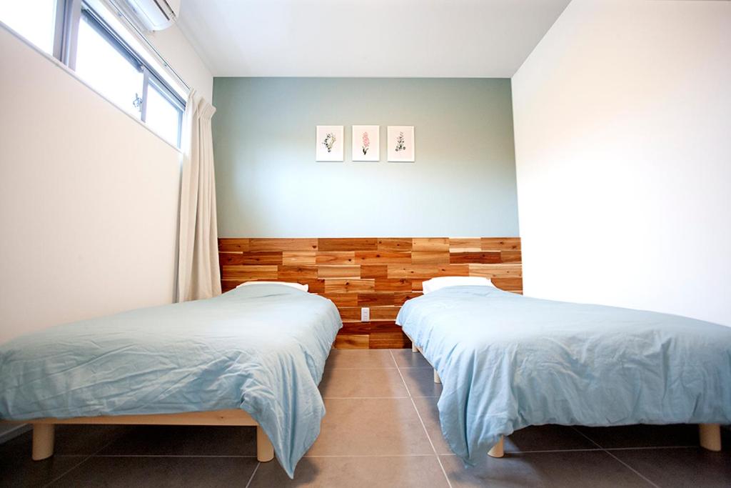 1 Schlafzimmer mit 2 Betten und einem Fenster in der Unterkunft Hichu House ハイチューハウス in Nago