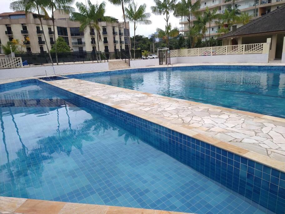 a swimming pool with blue water in a resort at Condomínio Buritis Centro de Bertioga a 100Mts da praia in Bertioga