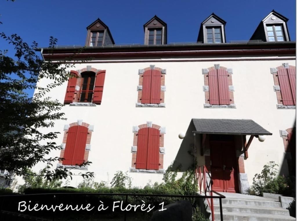 リュス・サン・ソヴァールにあるLe Florès Idéalement situé Centre Luz Appart T3 6 personnes Parkingの赤いドアと窓のある白い建物