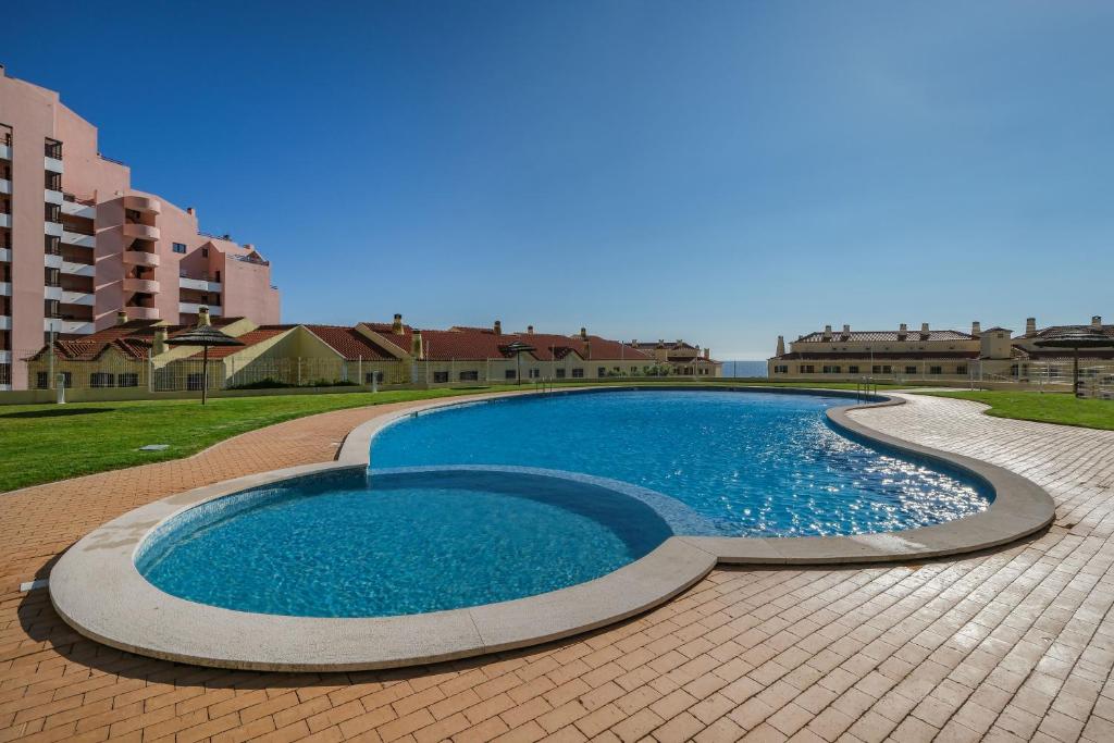 a large swimming pool on a tiled patio at Sea Lux Ericeira Beach in Ericeira