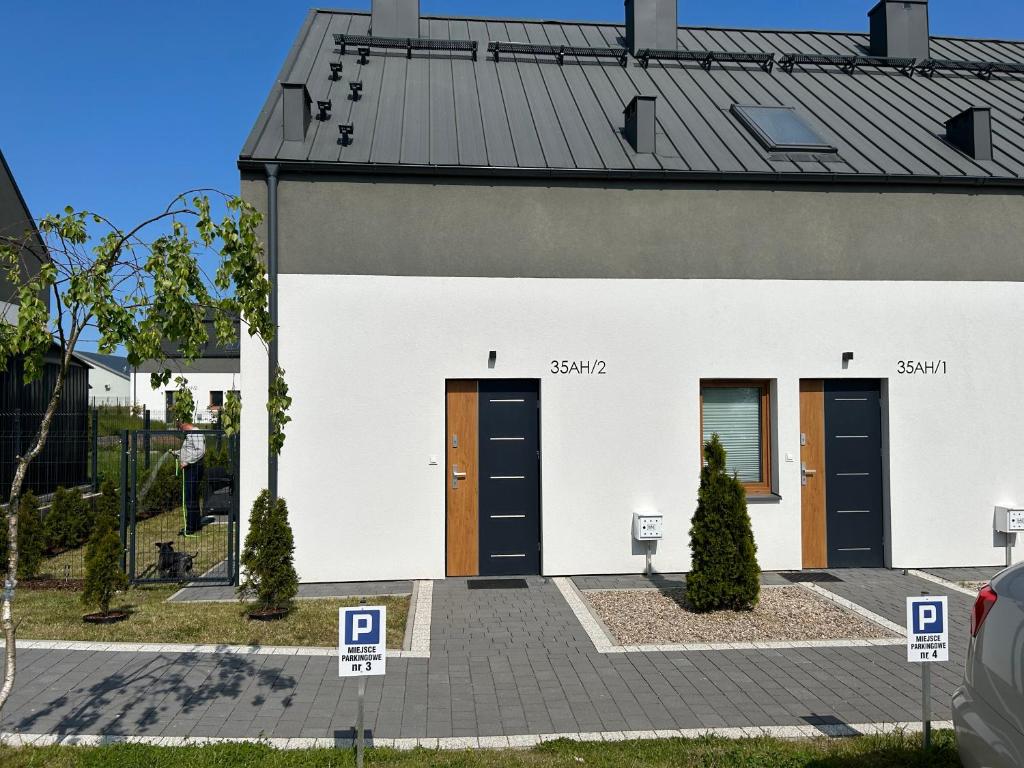 ein weißes Gebäude mit braunen Türen und einem Dach in der Unterkunft Apartament in Władysławowo