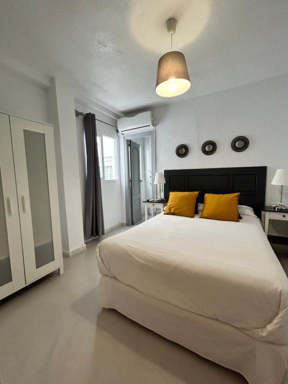 a bedroom with a large white bed with yellow pillows at Hostal Berlin in Marbella
