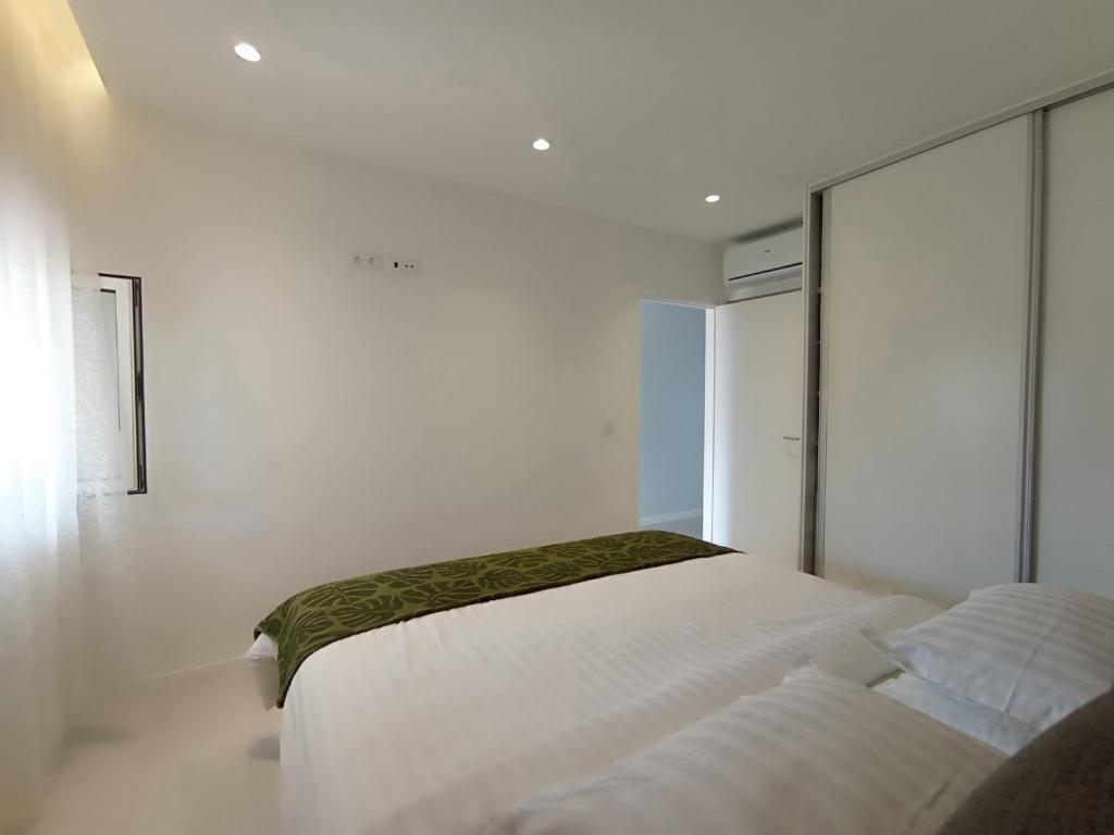 Habitación blanca con 2 camas y espejo. en Apartment Yulya en Albufeira