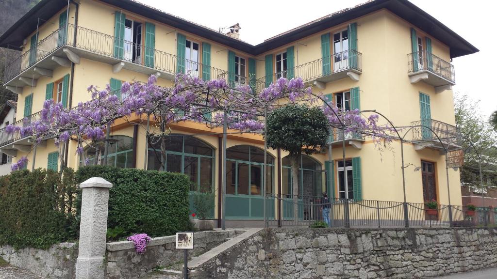 un gran edificio amarillo con flores púrpuras. en La Séca - Antico Albergo Alzese, en Pella