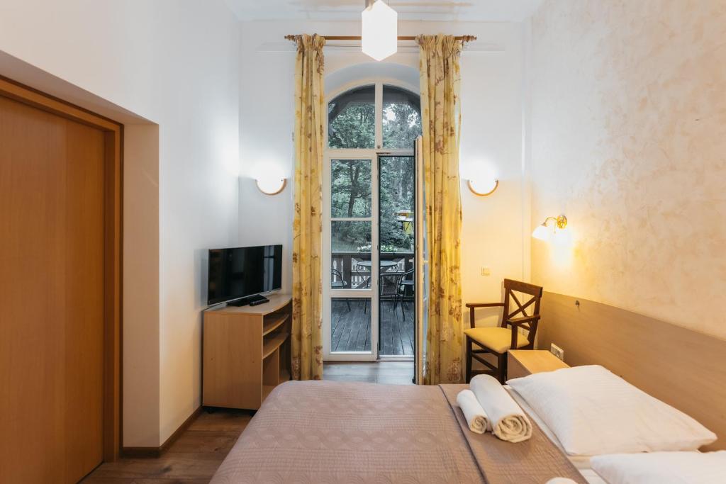 a bedroom with a bed and a tv and a window at Villa Bachmann - Kuršių kiemas in Juodkrantė