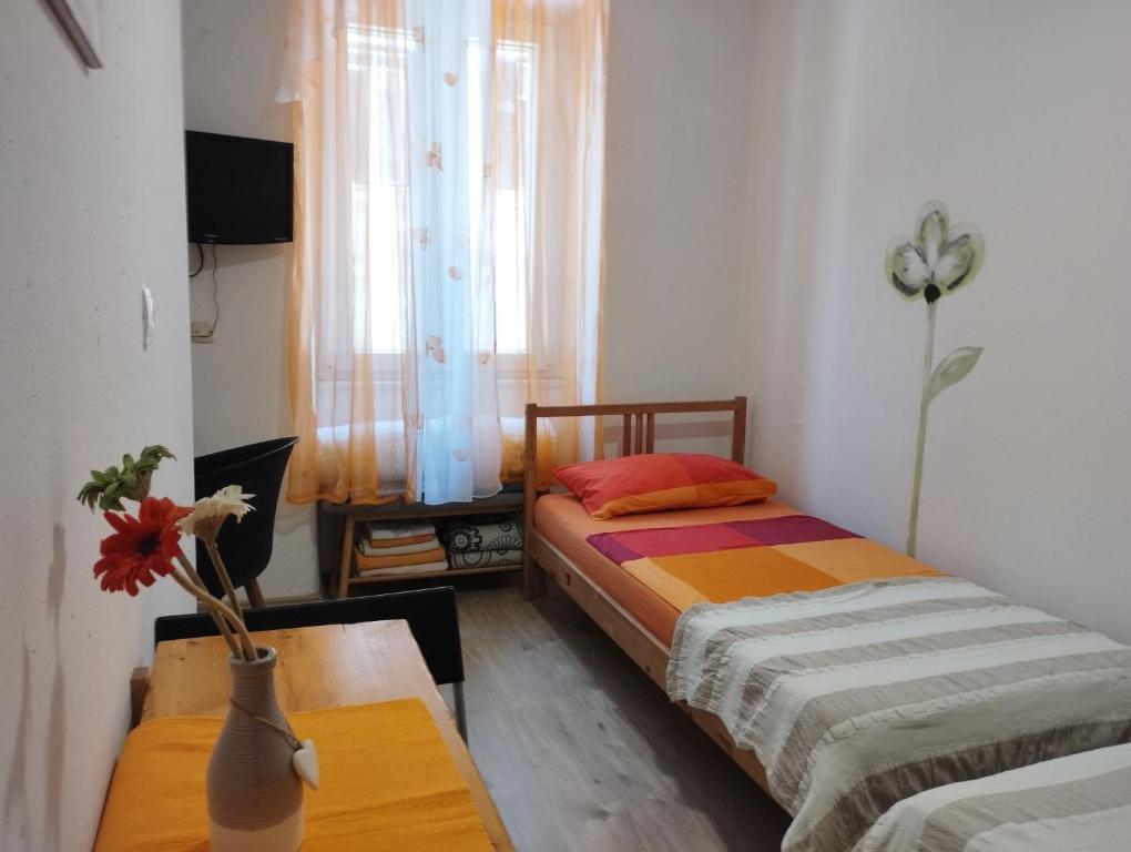 1 dormitorio con 2 camas y un jarrón de flores sobre una mesa en Old Town Room Pula, en Pula