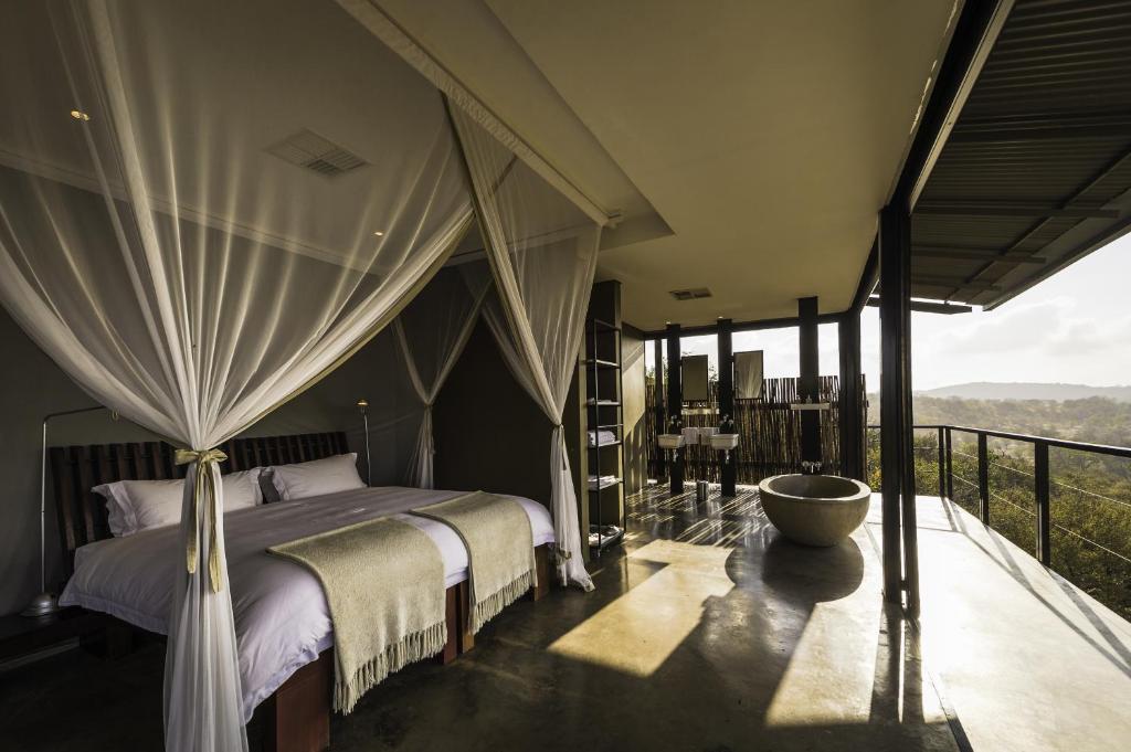 a bedroom with a bed and a balcony with a view at The Outpost & Pel's Post in Makuleke Contract Park