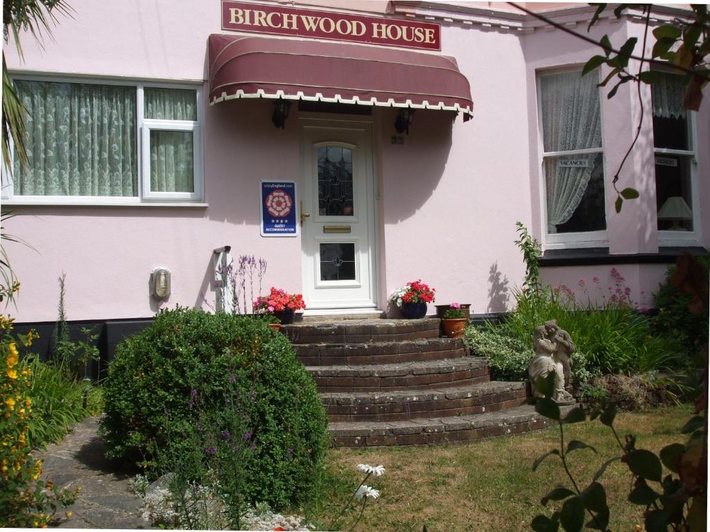 a pink house with stairs in front of it at Birchwood House in Paignton