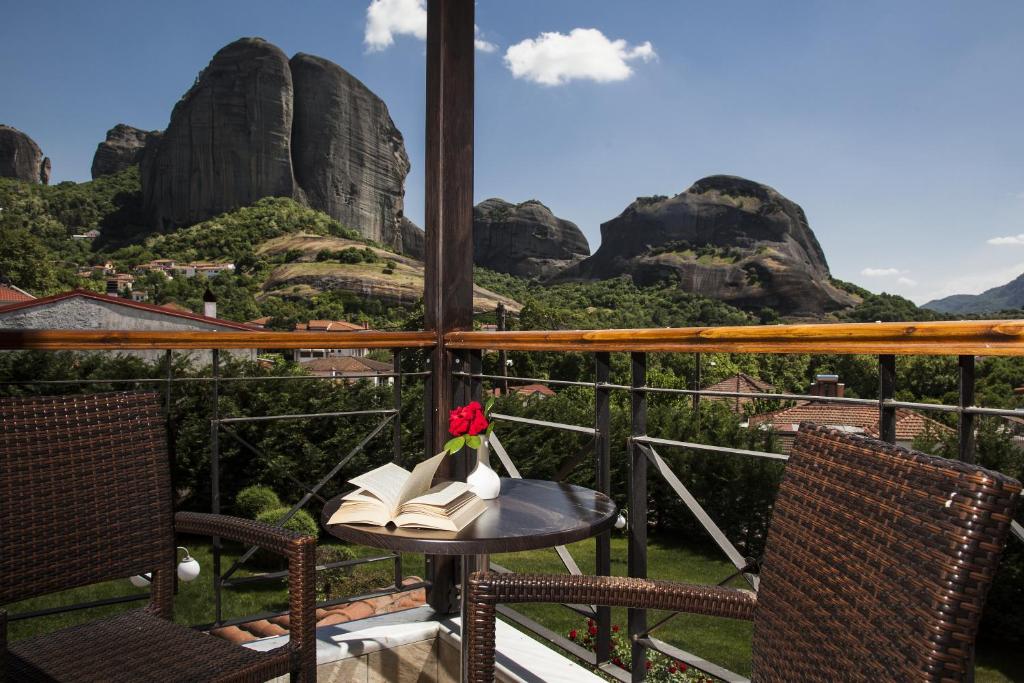 uma mesa com uma flor e livros numa varanda com montanhas em Hotel Meteoritis em Kalabaka