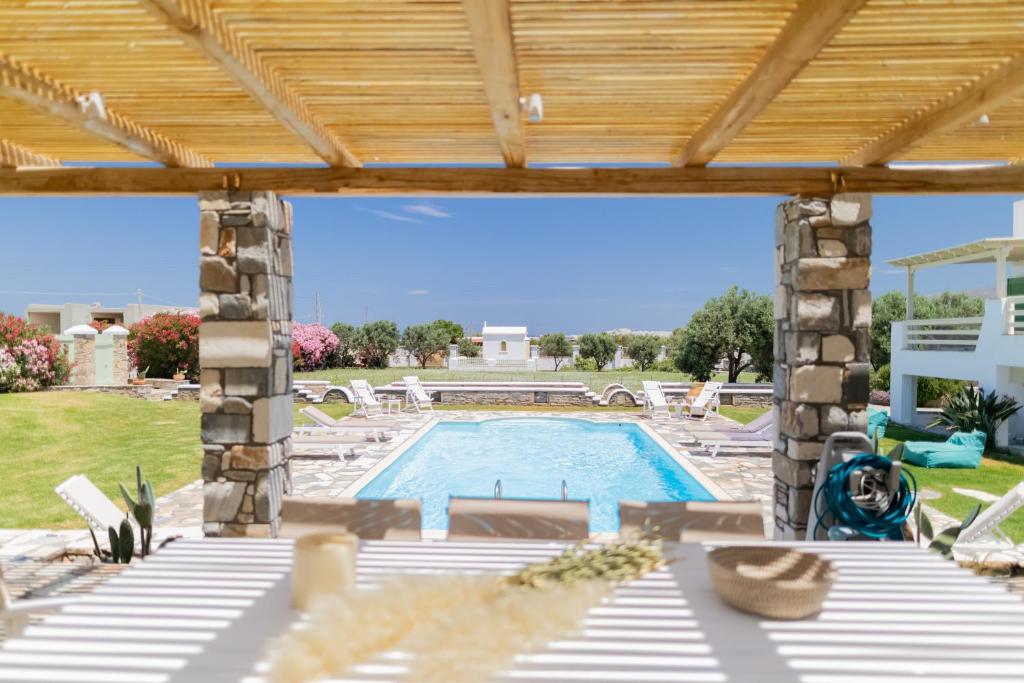 a patio with a swimming pool and a wooden pergola at JKG OIKIA in Agia Anna Naxos