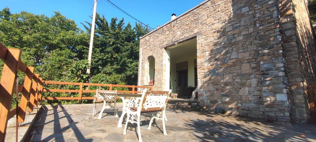 een patio met een tafel en stoelen voor een stenen gebouw bij Forest, sea, stone, junior suite in Tsagarada