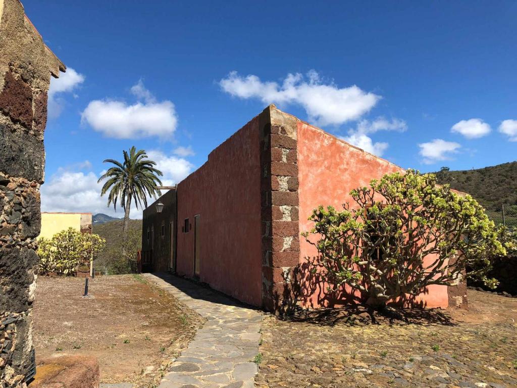 Un edificio de ladrillo con una palmera detrás. en Casa rural cerca de la costa de La Laguna 2 en La Laguna