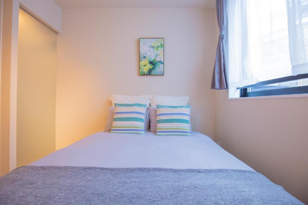 una camera da letto con un letto con due cuscini e una finestra di Your best choice for travel in Yoyogi EoY6 a Tokyo