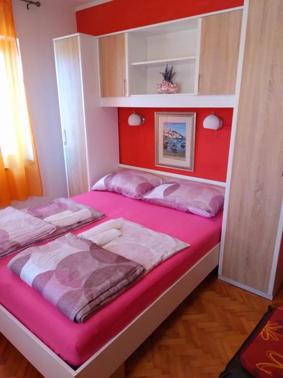 a bedroom with a large bed with pink sheets at Apartment Maya in Banjole