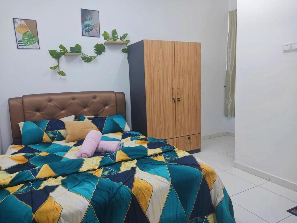 Un dormitorio con una colorida cama con almohadas moradas en TOP Muzaffar Homestay, en Ayer Keroh