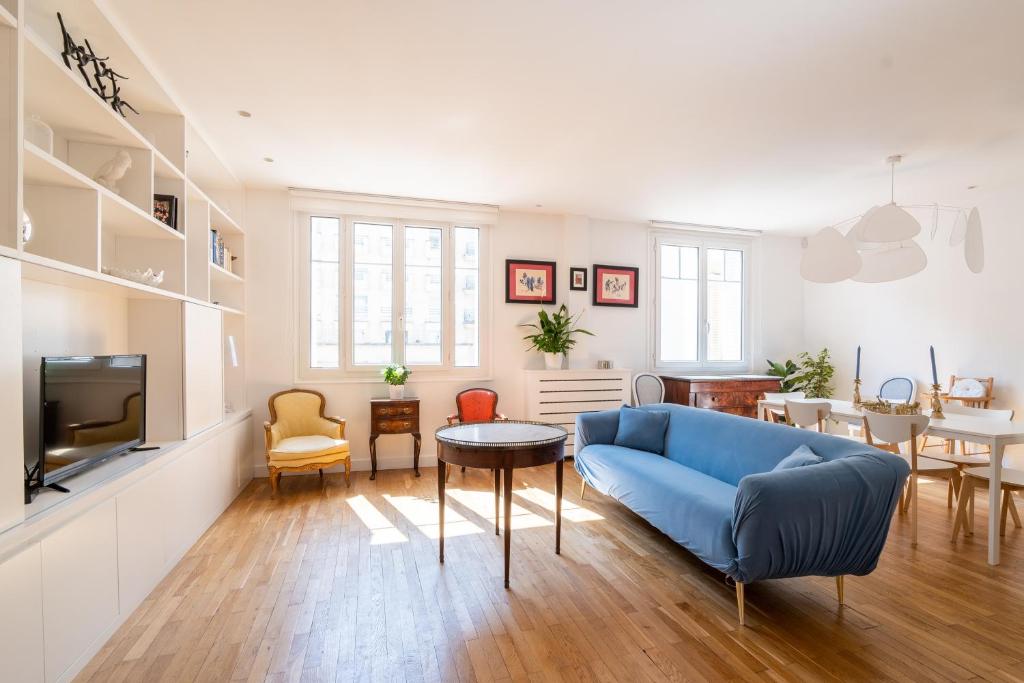 uma sala de estar com um sofá azul e uma mesa em Veeve - Ethereal Light em Paris