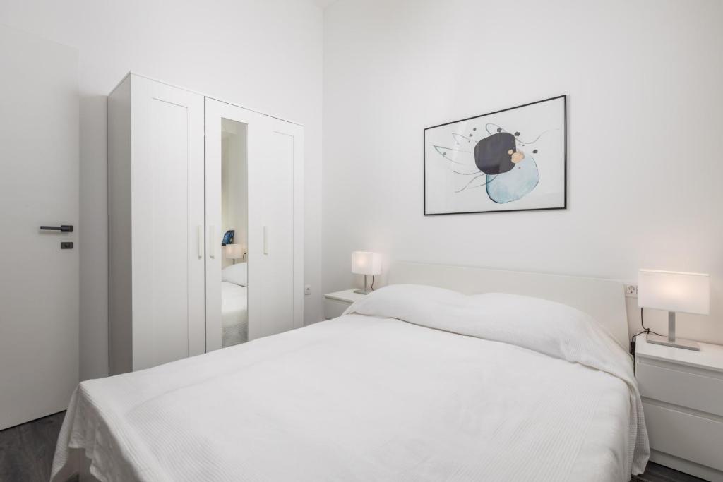 a white bedroom with a bed and a mirror at Apartment with balcony Nest In 2 in Rijeka