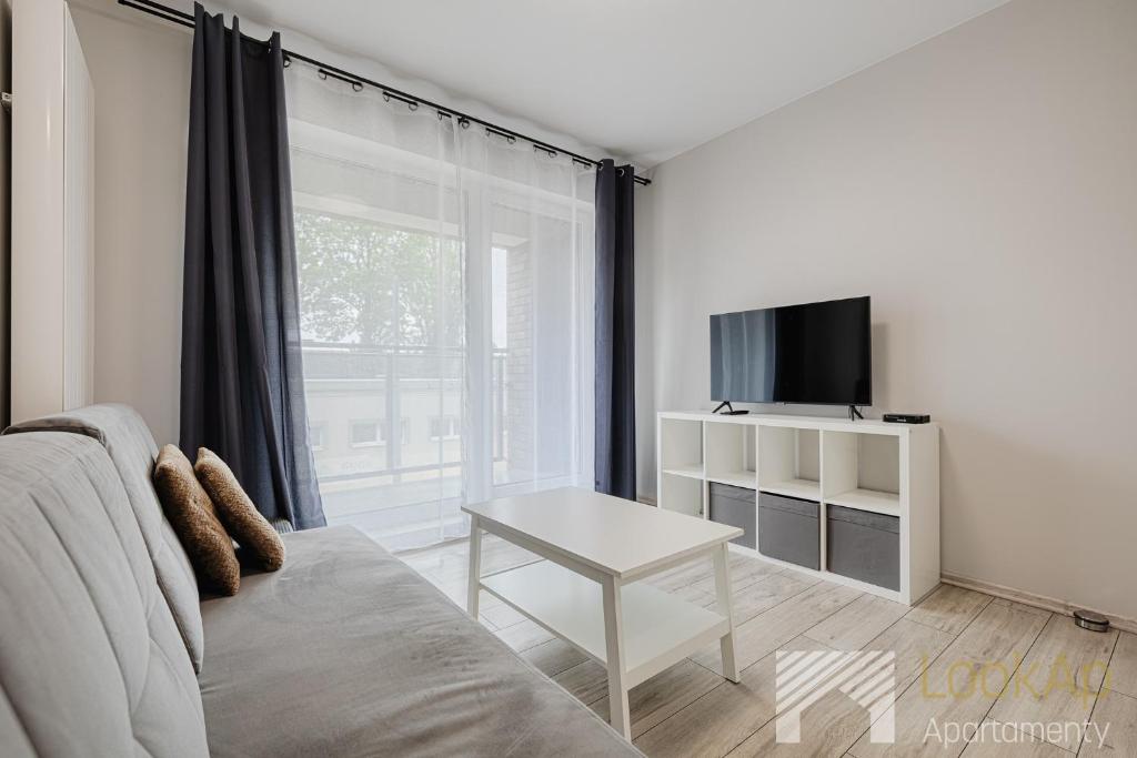 a living room with a couch and a tv and a table at Primo V by LookAp in Łódź