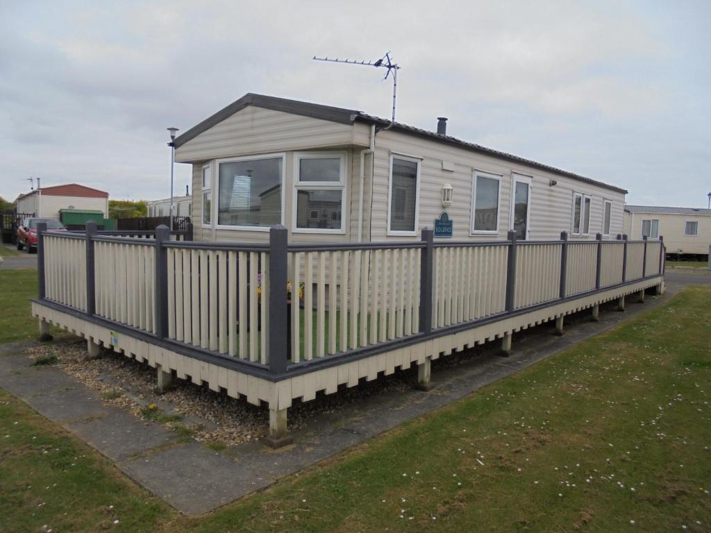 a mobile home with a fence in a yard at The Grange: Solstice:- 6 berth, enclosed veranda in Ingoldmells