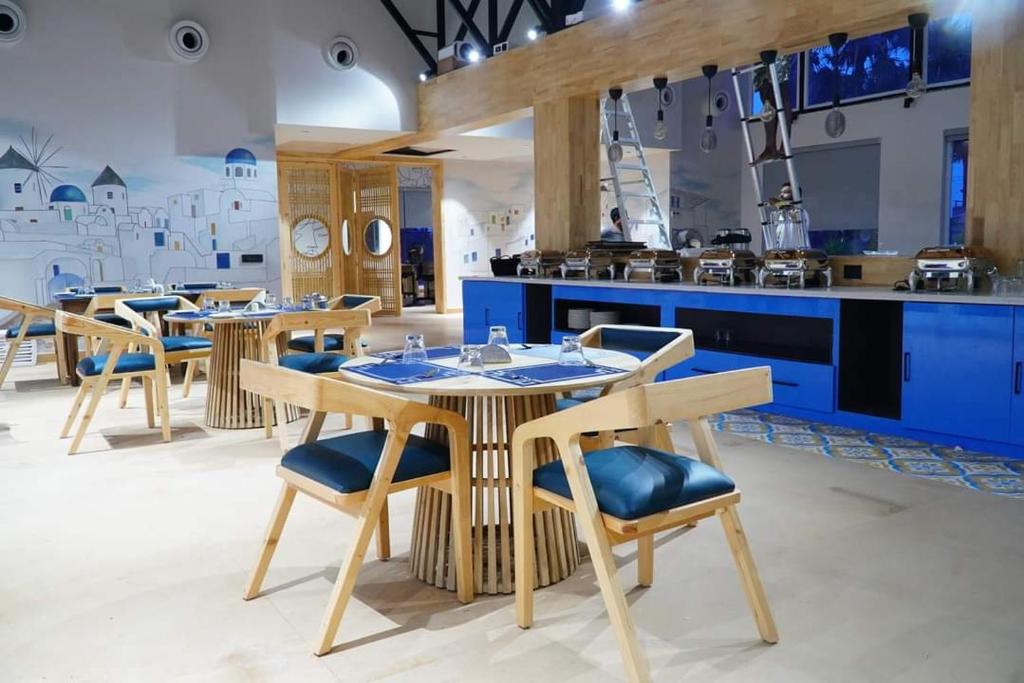 een restaurant met houten tafels en stoelen en een keuken bij V Hotels and Resorts in Chīrāla