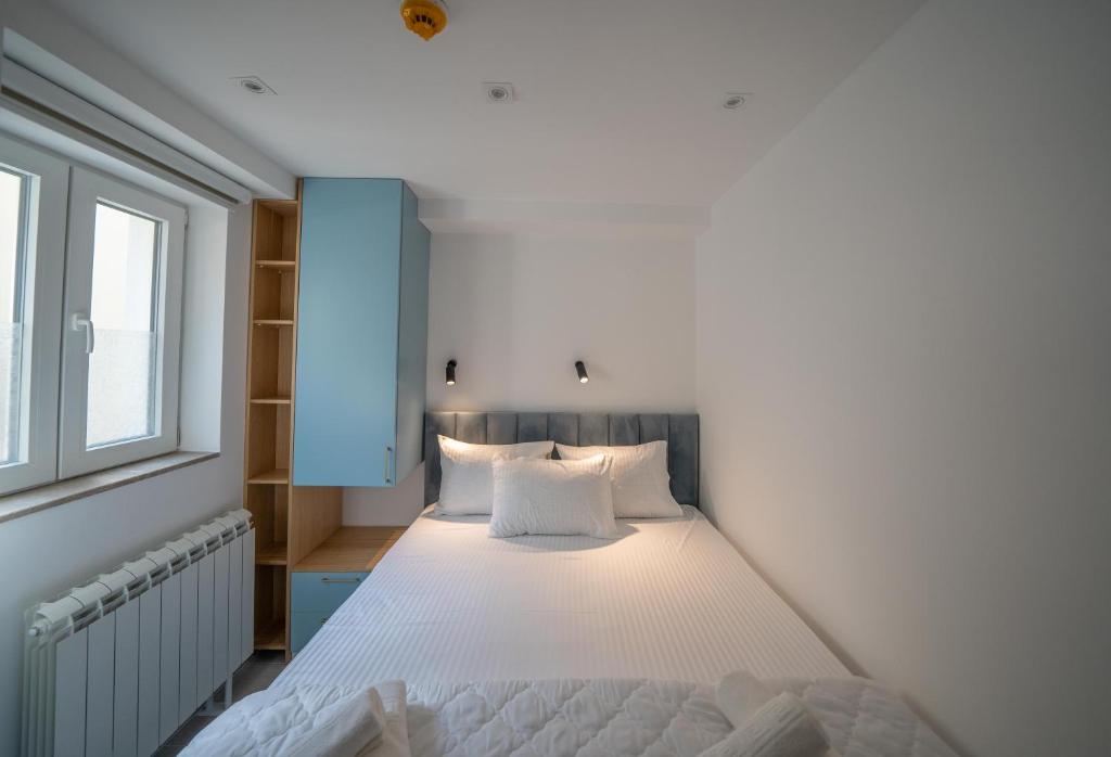 1 dormitorio con 1 cama con sábanas blancas y ventana en Ocea apartments in the city center en Kotor