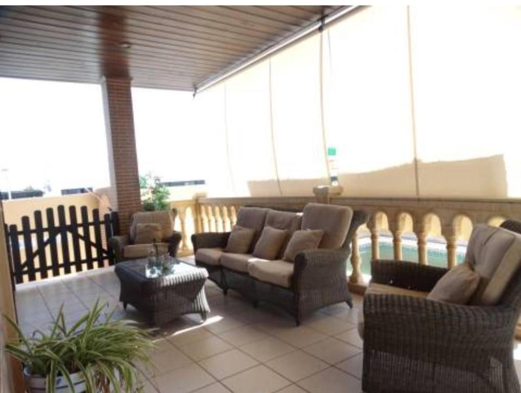 une terrasse couverte avec des canapés et des chaises sur un balcon dans l'établissement Casa Particular, à Aljaraque