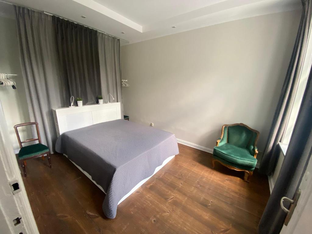ソポトにあるHome3city Kameralnyのベッドルーム1室(ベッド1台、緑の椅子2脚付)
