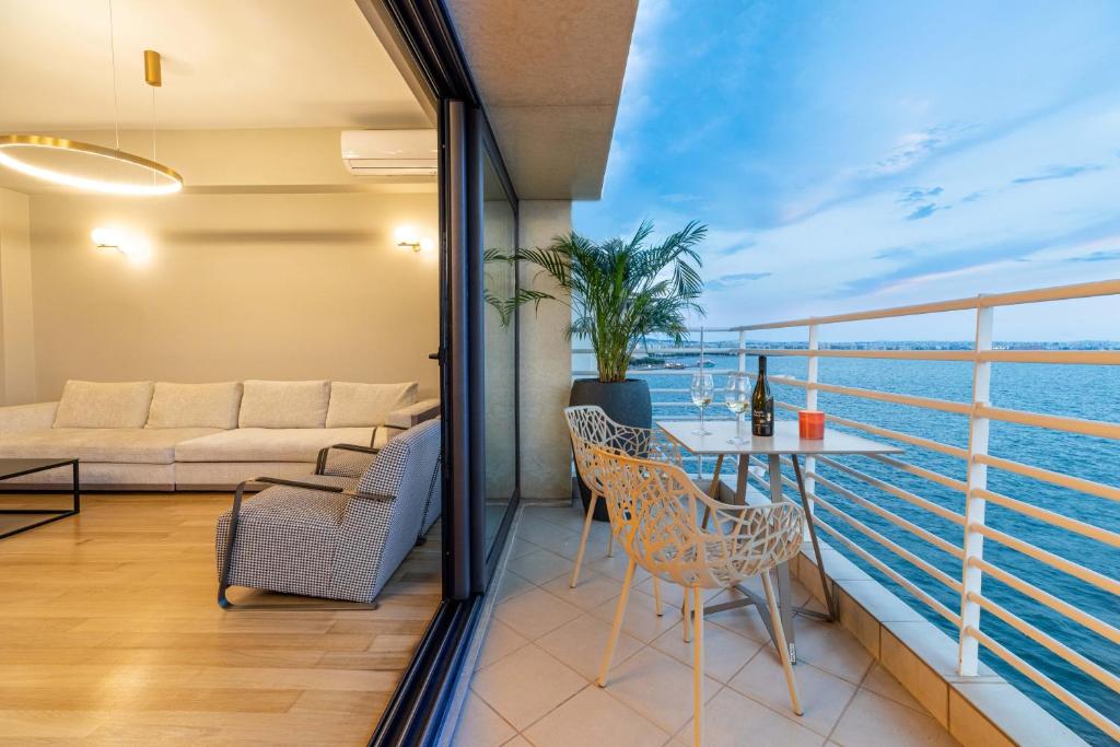 a room with a balcony with a table and chairs at ICONIC SALONICA SUITE seafront in Thessaloniki