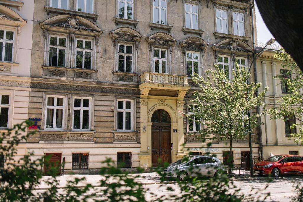 un grand bâtiment avec des voitures garées devant lui dans l'établissement Girls Hostel, à Cracovie