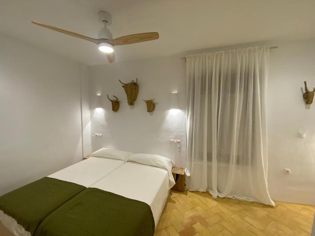 a bedroom with a bed and a ceiling fan at Doñana Suite Casa-Hotel in El Rocío