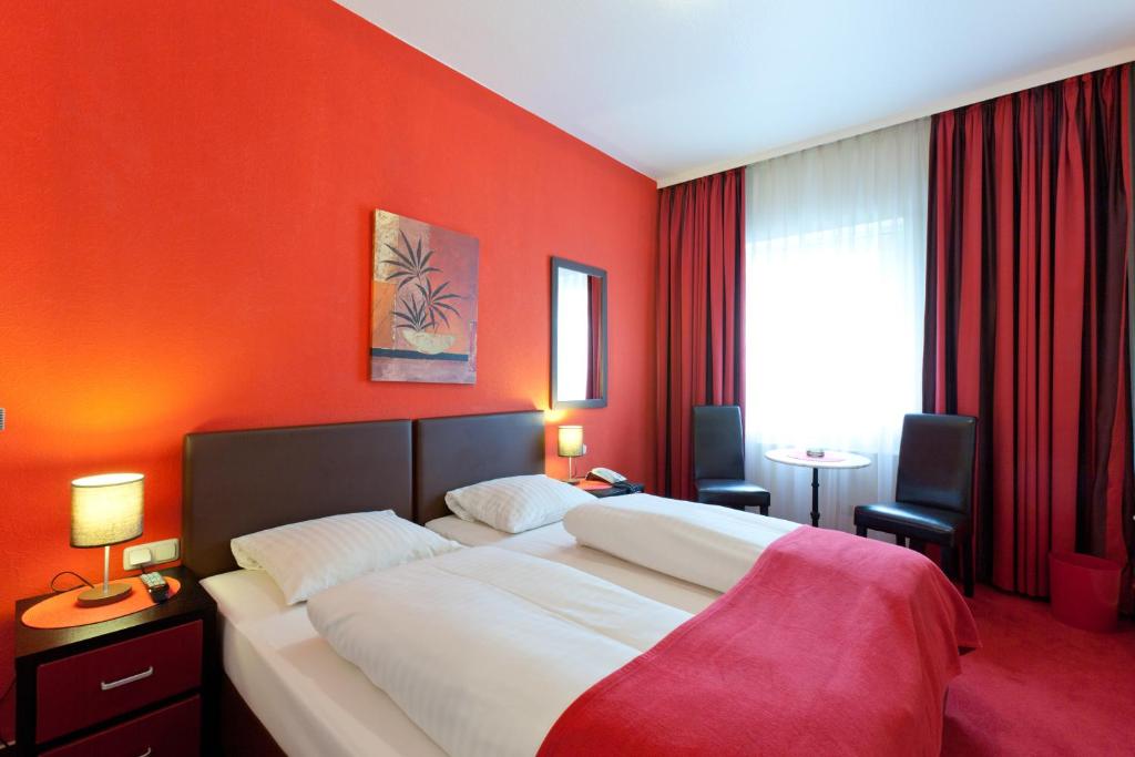 ハンブルクにあるホテル インペリアルのベッドルーム1室(オレンジ色の壁の大型ベッド1台付)