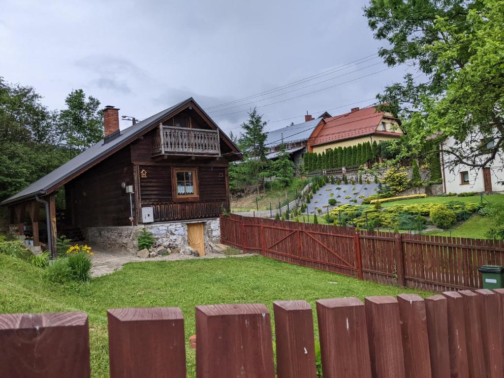 a wooden house with a fence in front of a yard at Góralski domek w Kluszkowcach in Kluszkowce