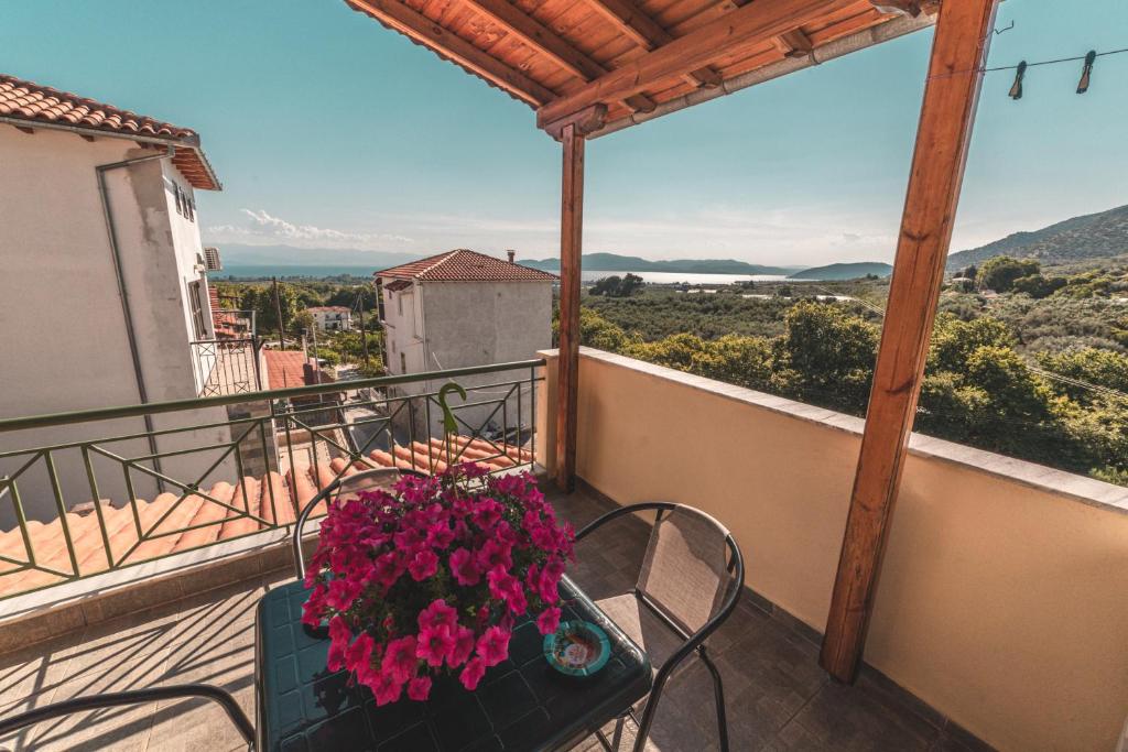 - un balcon avec une table, des chaises et des fleurs dans l'établissement Pelion Charming Cottage, Panoramic Seaview Retreat, à Vólos