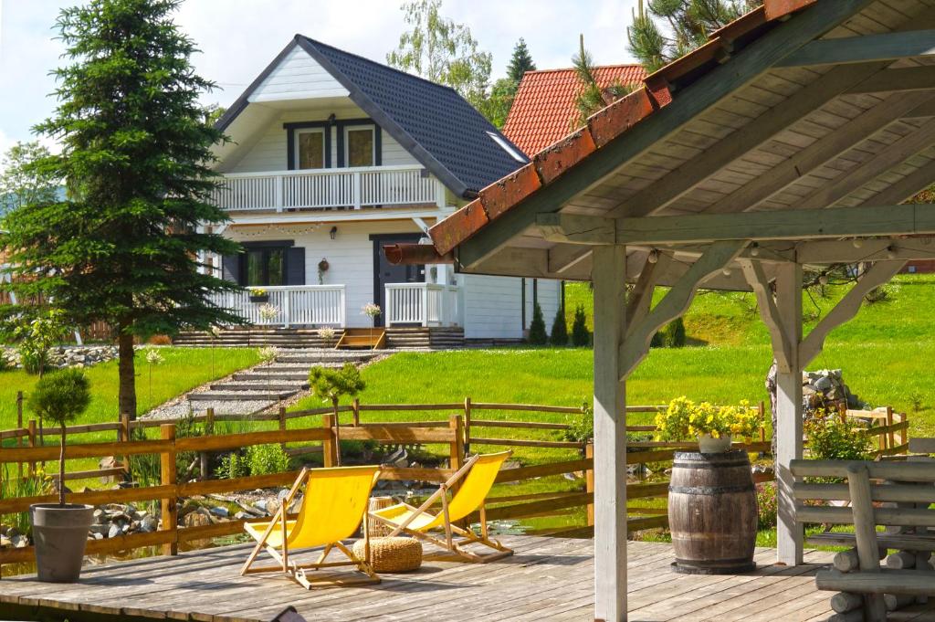 una terraza con sillas amarillas y una casa en Domki Nad Potokiem574067621 en Ustrzyki Dolne