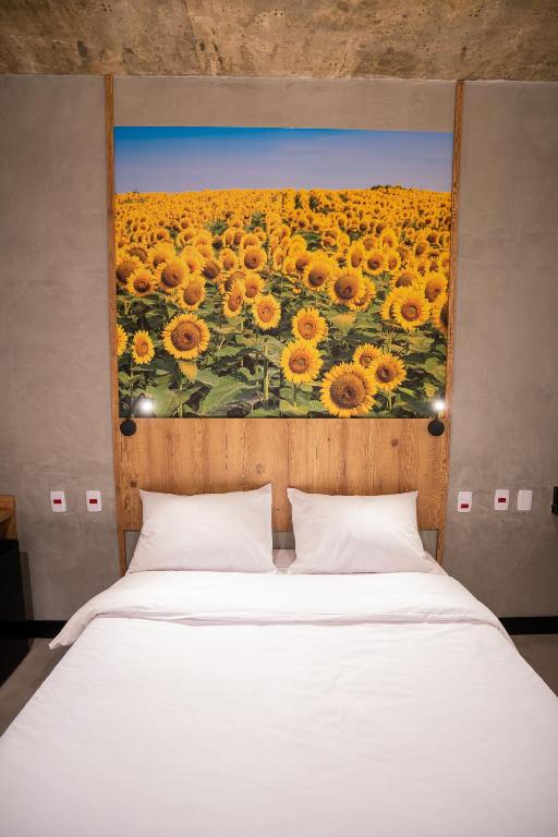 a bed with a painting of a field of sunflowers at CAMPOS DE HOLAMBRA INN in Paranapanema