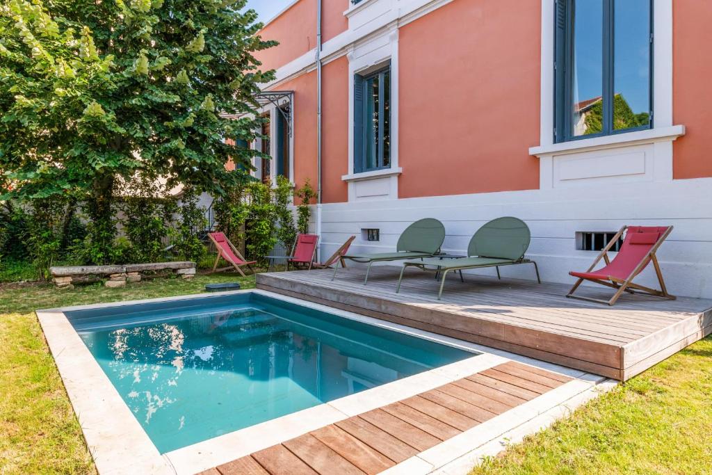 una piscina con sillas y una casa en Villa with pool and garden close to Lyon - Welkeys, en Champagne-au-Mont-d'Or