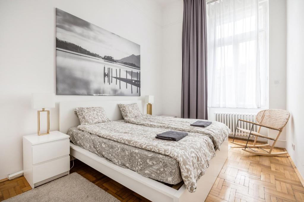 a white bedroom with a bed and a chair at Elegant Apartment in Super Central Location in Budapest