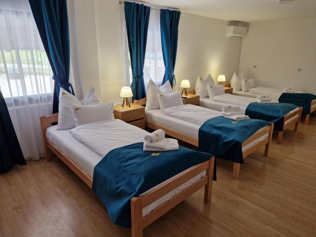 3 camas en una habitación de color azul y blanco en Restoran Leburic, en Prnjavor