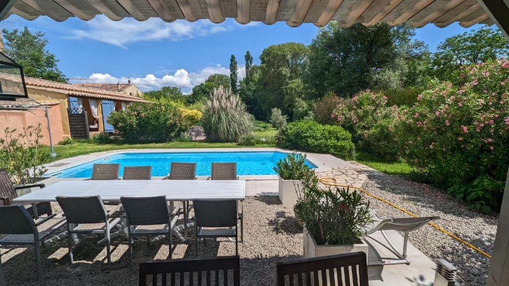 a patio with a table and chairs next to a swimming pool at La Belle Rivière in Salernes