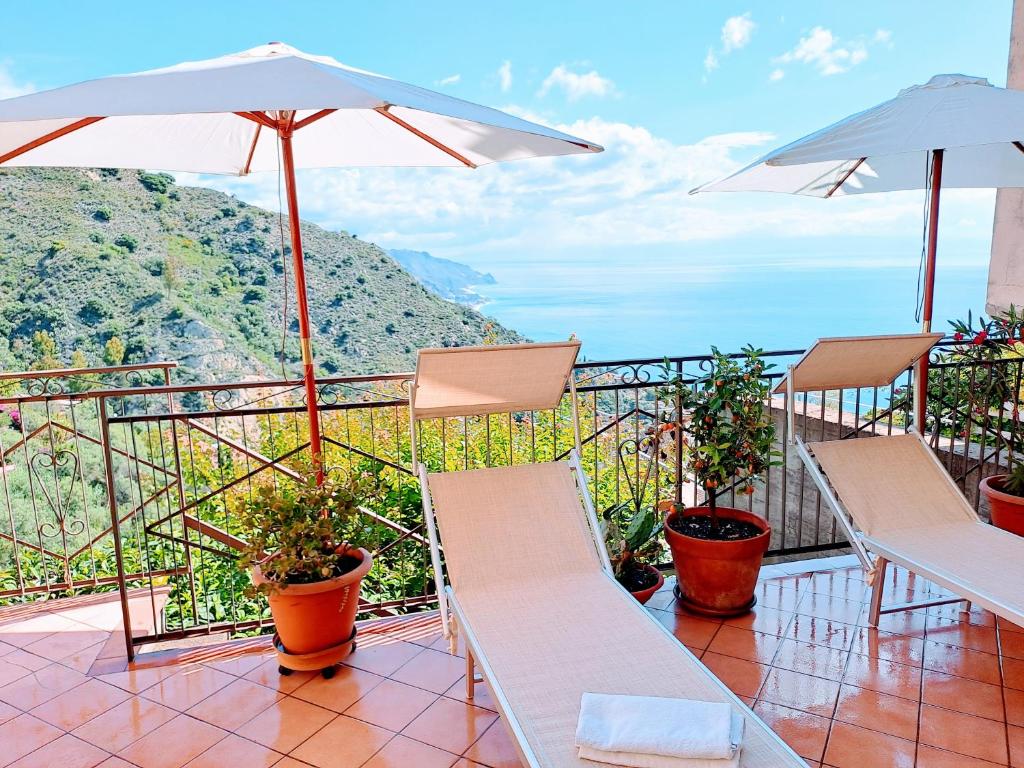 a balcony with chairs and umbrellas with a view at Castel Tauro Apartment in Taormina