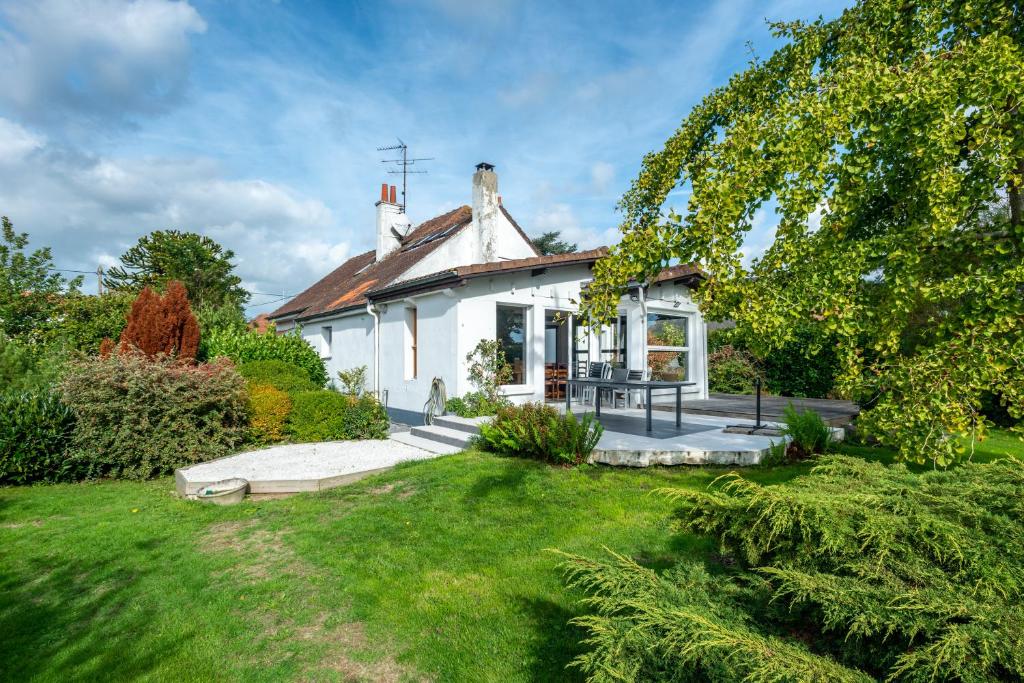 une petite maison blanche avec une cour gazonnée dans l'établissement Grande Maison Familliale, à Coulogne