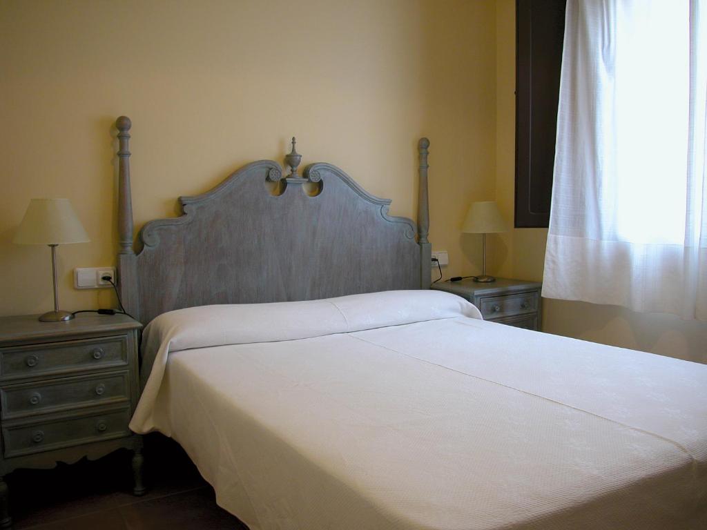 um quarto com uma grande cama branca com duas mesas de cabeceira em APARTAMENTS PUIG GILI em Mura