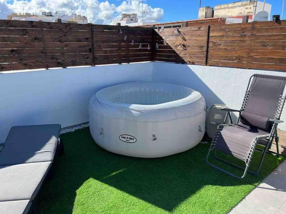 a large white tub sitting on a patio with two chairs at Apartamento AGUA con Jacuzzi y terraza in Las Palmas de Gran Canaria